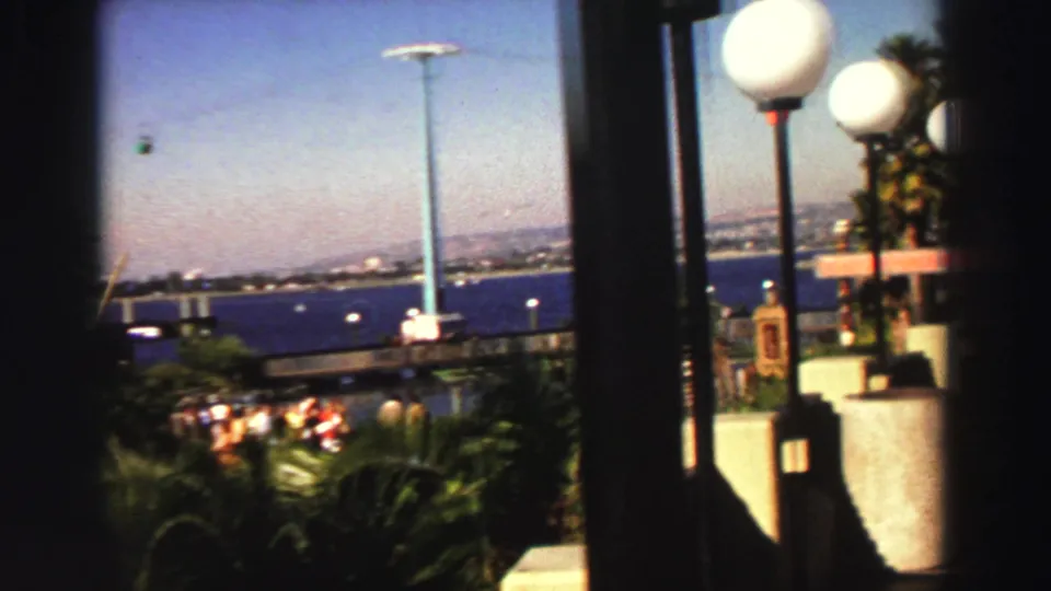 1969 Lake Tahoe resort view with spherical lamps, palms, railings, blue water, and distant shore beyond.
