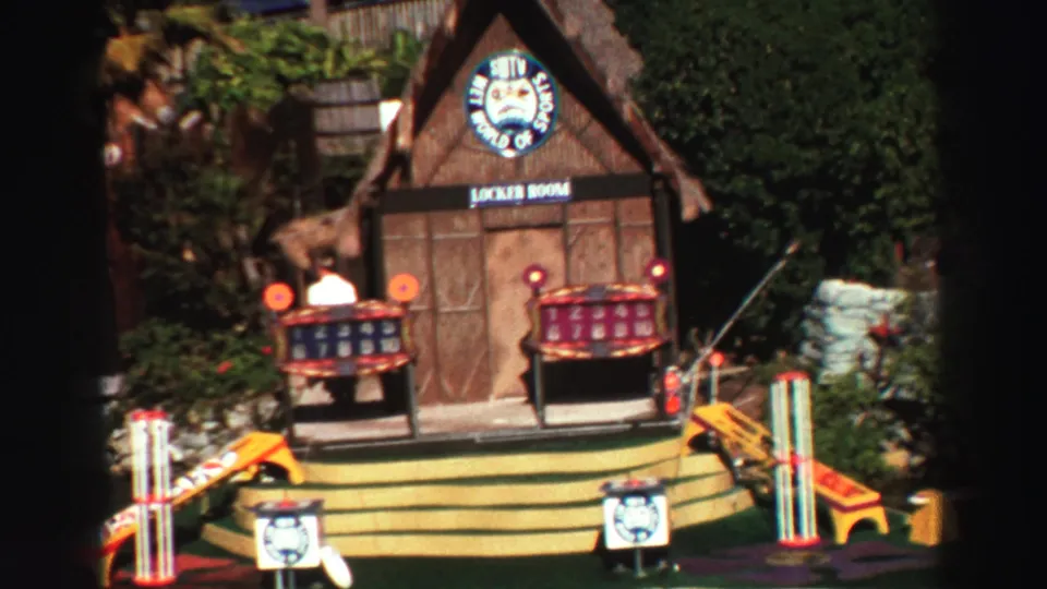 1969 Lake Tahoe home-movie close-up of the floating mini golf lodge with Silly World of Sports signage and painted obstacles.