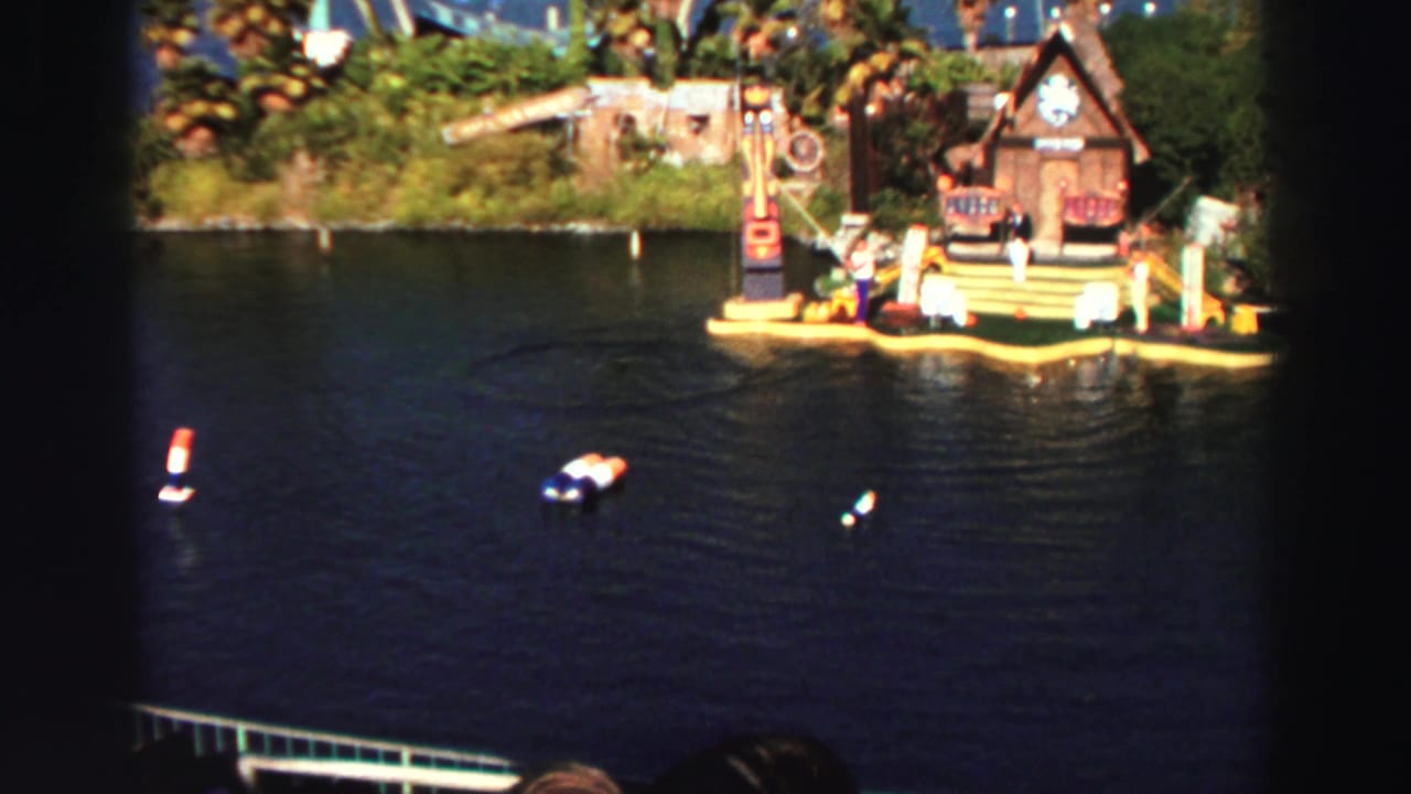 Floating water-show stage on dark lake water with spectators and small boats nearby.