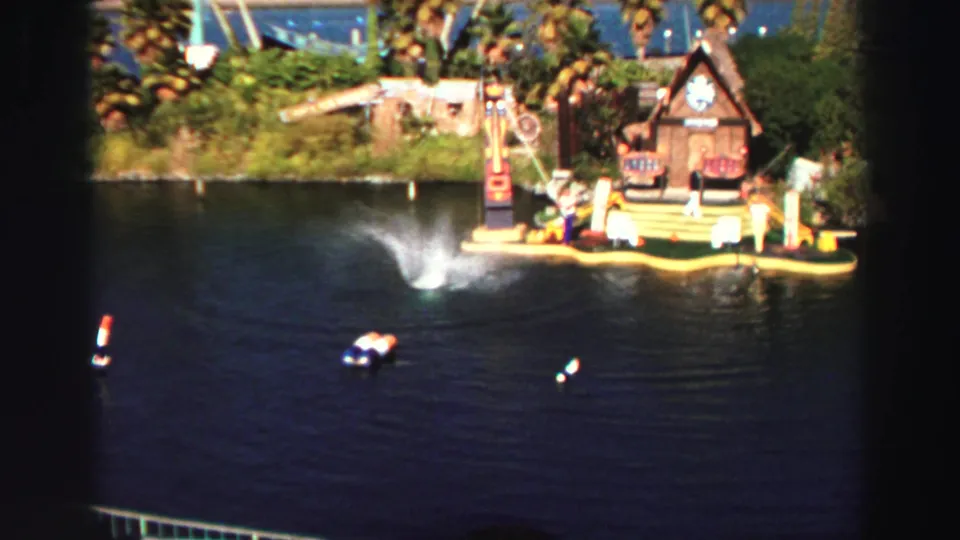 1969 Lake Tahoe home-movie frame showing a large dolphin splash near the stage with boats and spectators visible.