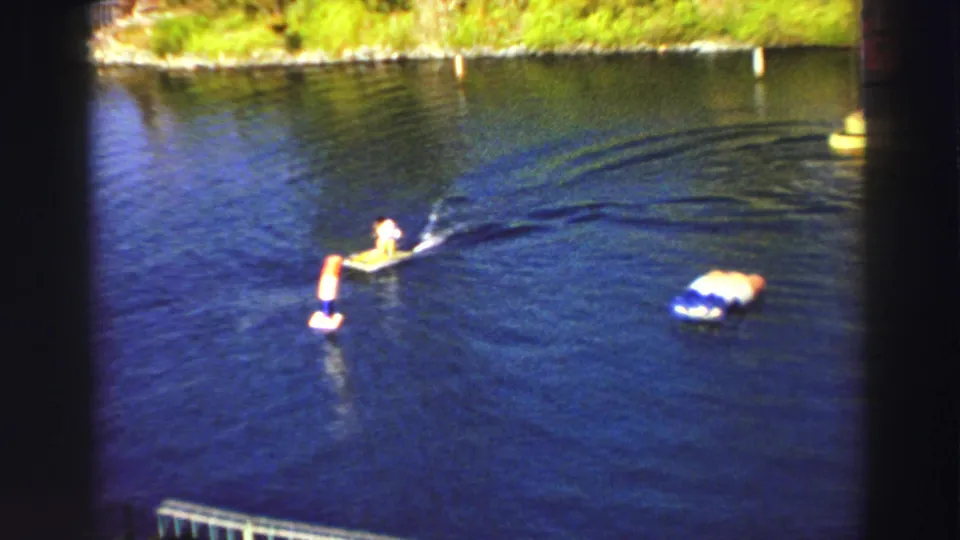 1969 Lake Tahoe frame showing the monkey in a white outfit steering past a buoy-like obstacle, with a larger floating marker nearby.