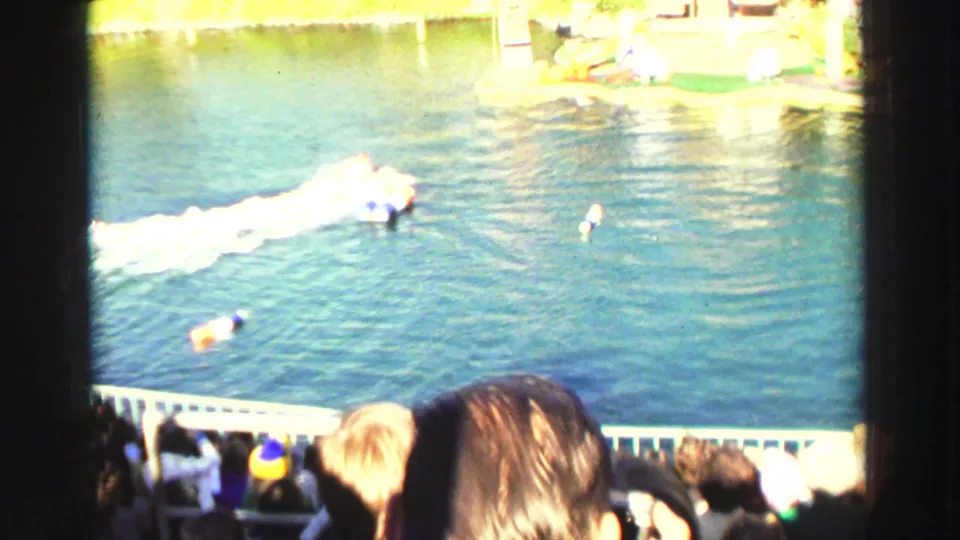 Visitor-shot Lake Tahoe water show scene with spectators in the foreground, buoys on the water, and a white wake crossing the performance area.