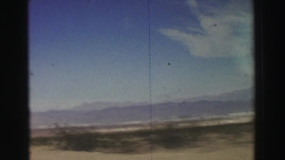 The frame shows a wide arid landscape near Lake Tahoe, with low brush, distant mountains, blue sky, and visible 8mm frame edges.