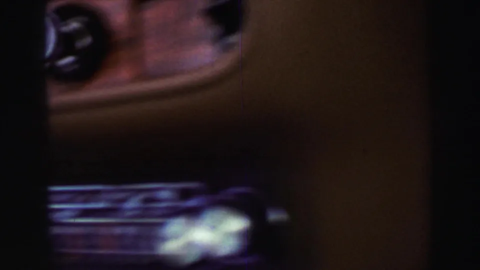 Soft, dark 8mm frame from inside the vehicle, showing part of the car interior during the road trip footage.