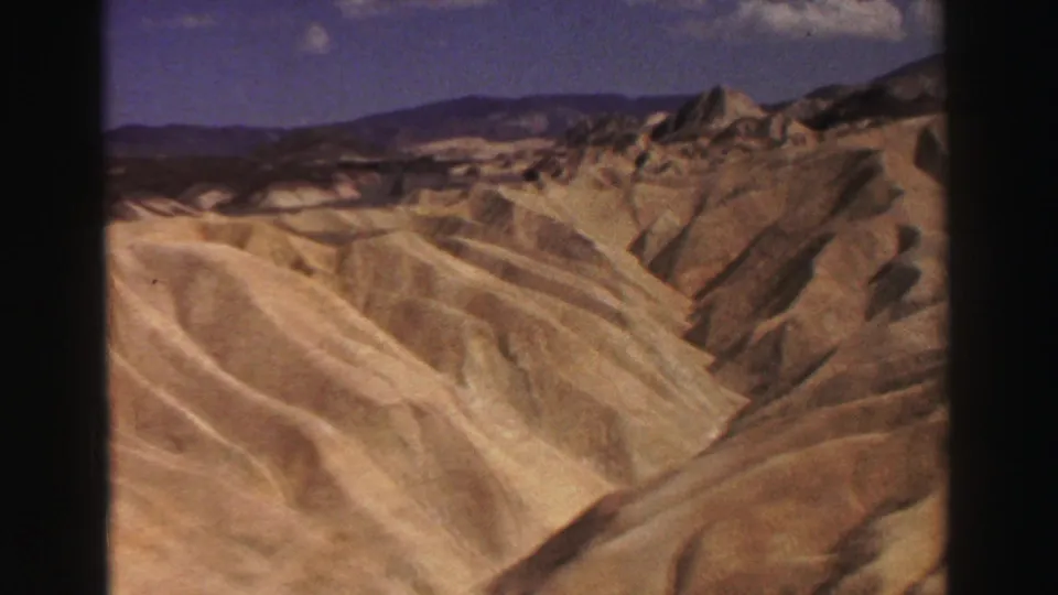 1969 8mm landscape view of pale, eroded California hills and darker distant ridges, filmed during a road trip.