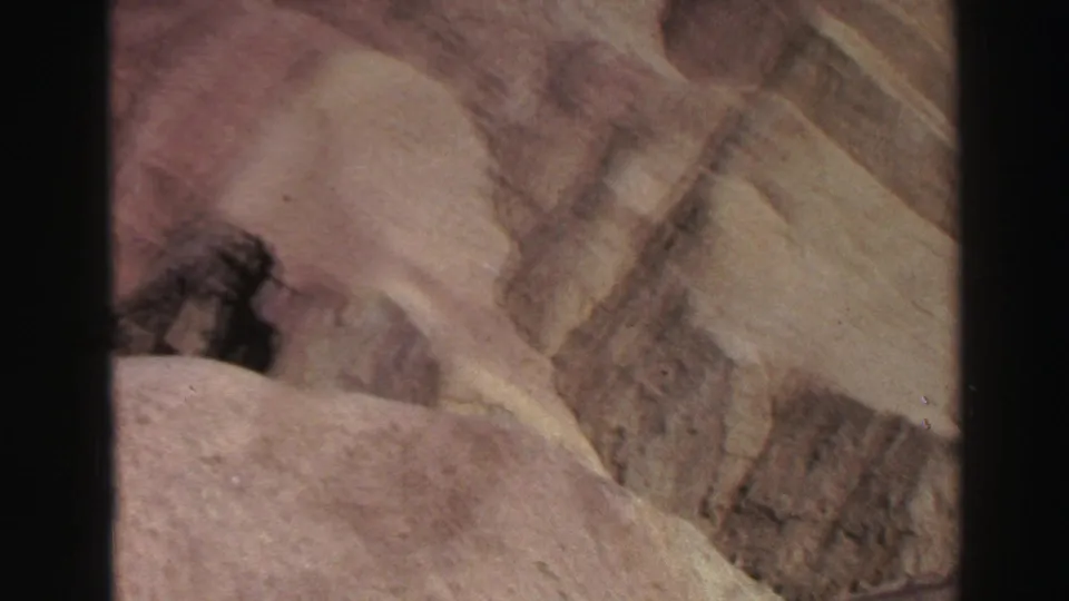 1969 8mm Lake Tahoe-area landscape frame showing pale sandy slopes, canyon-like cuts, and exposed textured earth.