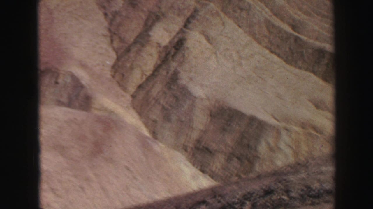 Sunlit tan canyon rocks with layered surfaces and dark film borders.