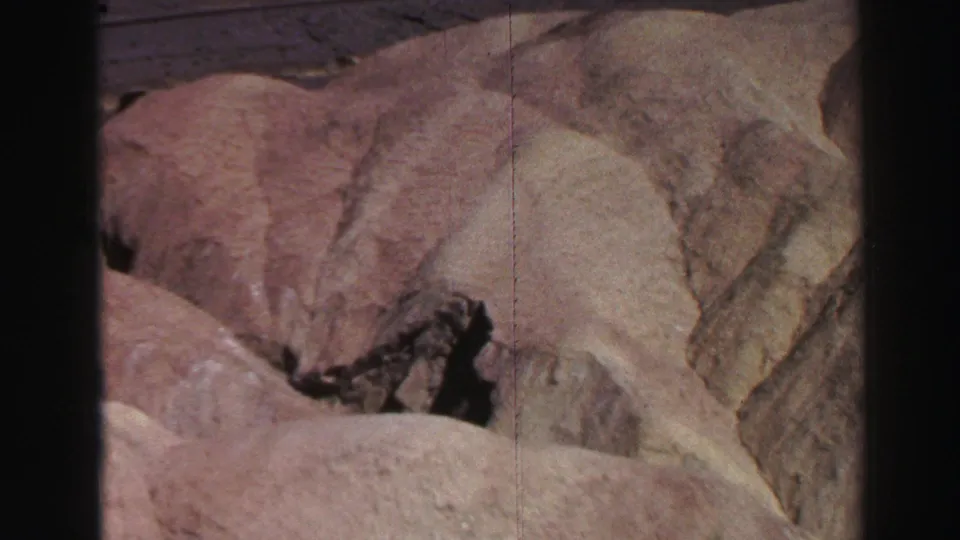 1969 Lake Tahoe-area canyon view with rounded pale rocks, a dark crevice, and small vegetation in the rock gap.