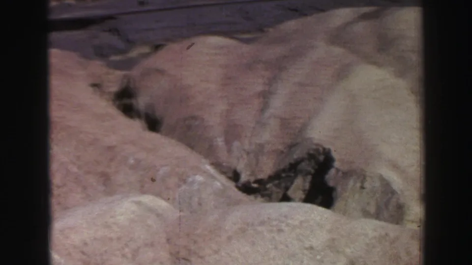 1969 Lake Tahoe-area 8mm frame showing pale canyon slopes, a shadowed crack, and textured rock surfaces.