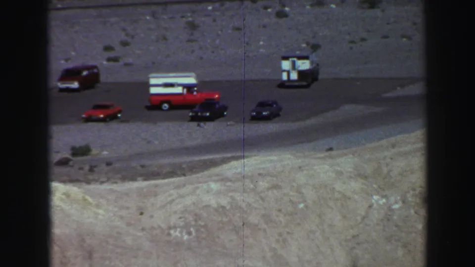 Red-and-white pickup truck and classic cars at a Lake Tahoe roadside overlook in 1969 8mm home-movie footage.