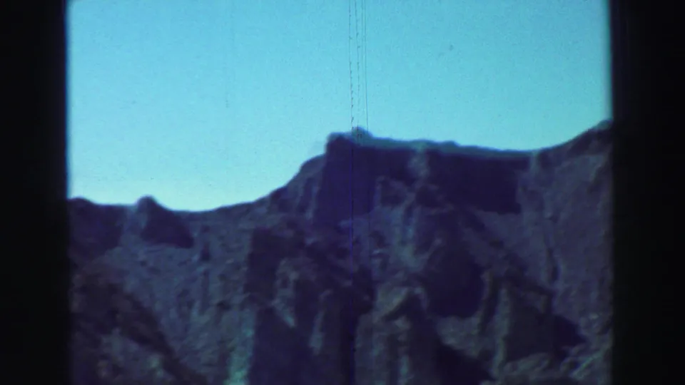 Mountain slopes near Lake Tahoe appear under clear blue sky, with soft focus and visible 8mm film scratches.