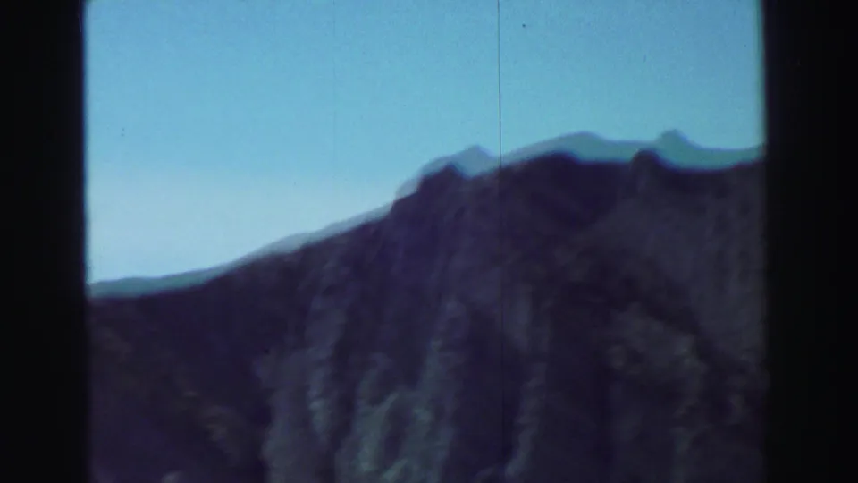 Lake Tahoe mountain landscape from 1969 home-movie footage, showing a rocky ridge, blue sky, and visible film wear.