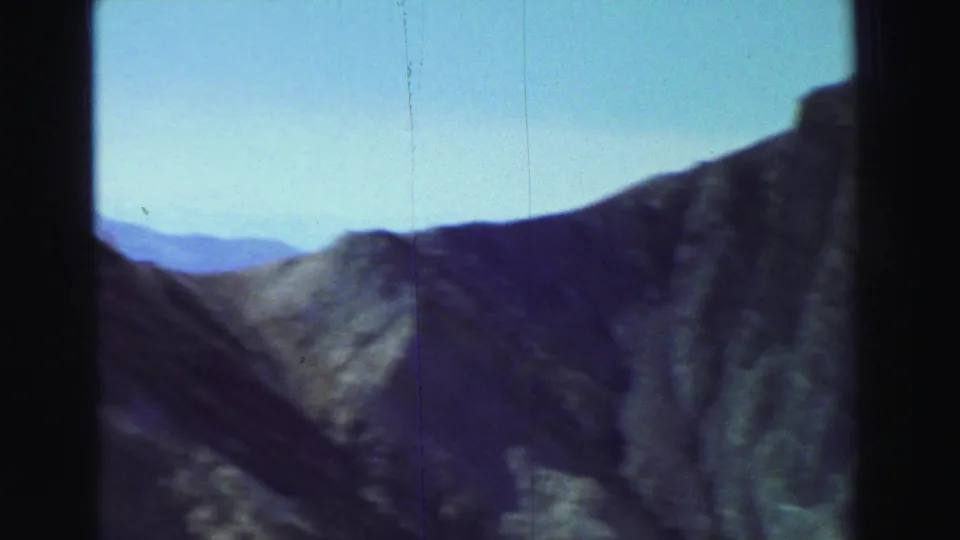 1969 Lake Tahoe-area 8mm frame showing rugged mountain terrain viewed from above or through a window, with visible film gate edges.