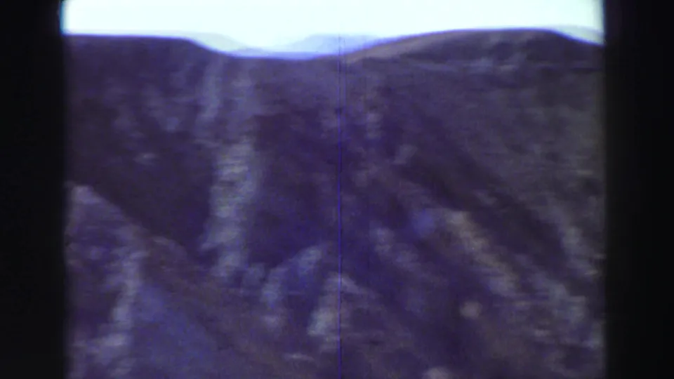 Lake Tahoe-area mountain ridges appear in a soft, grainy 8mm frame with a dark vertical border through the center.