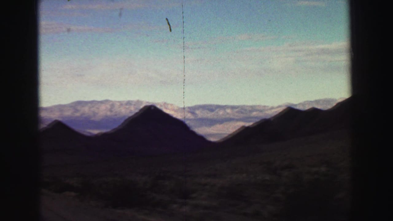 Dark mountain silhouettes and distant ridges seen through 8mm frame borders.