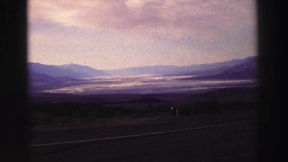 1969 Lake Tahoe area landscape view from the road, with layered mountains, haze, and a dark foreground shoulder.