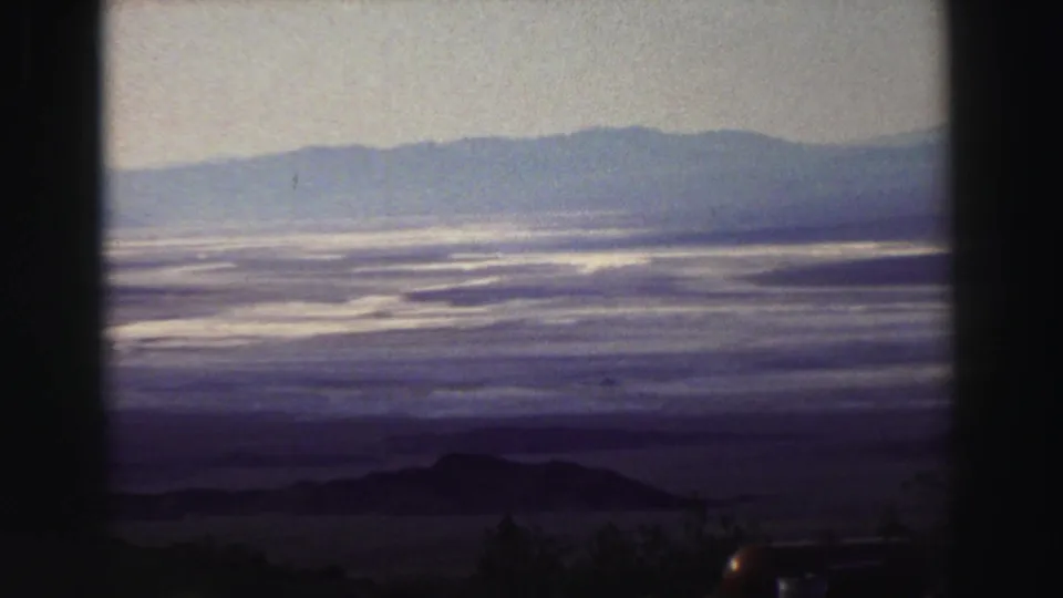 Lake Tahoe landscape on 8mm film, with a broad reflective lake, distant ridge, and shadowed foreground terrain.
