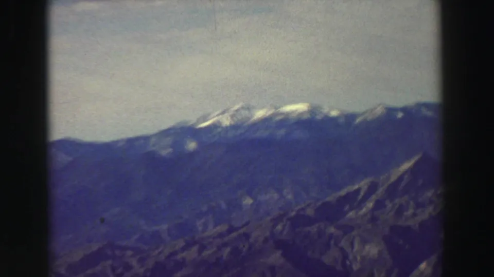 Distant Lake Tahoe region mountain range appears in a blue-toned 1969 8mm frame with visible grain and film-edge shadow.