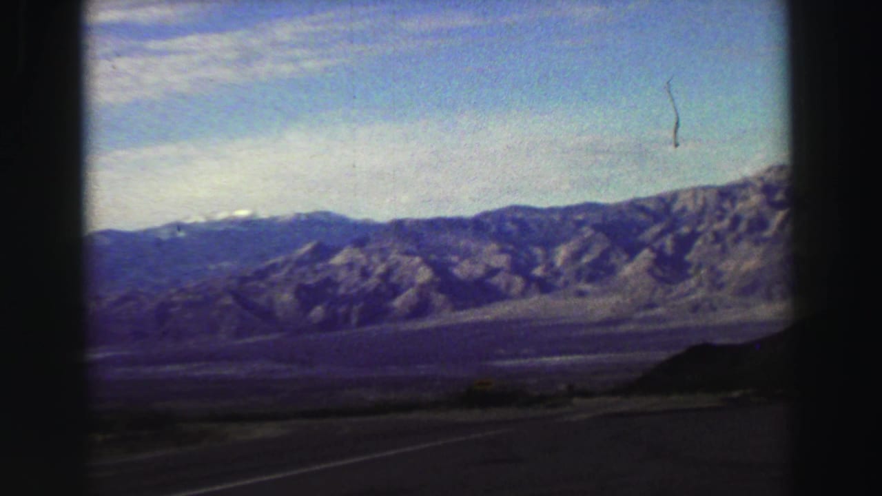 Mountain ridge and valley seen through dark car-window edges.