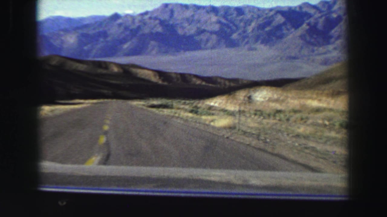 1969 8mm view from inside a car on a paved road through dry mountainous terrain in the Lake Tahoe, California area.
