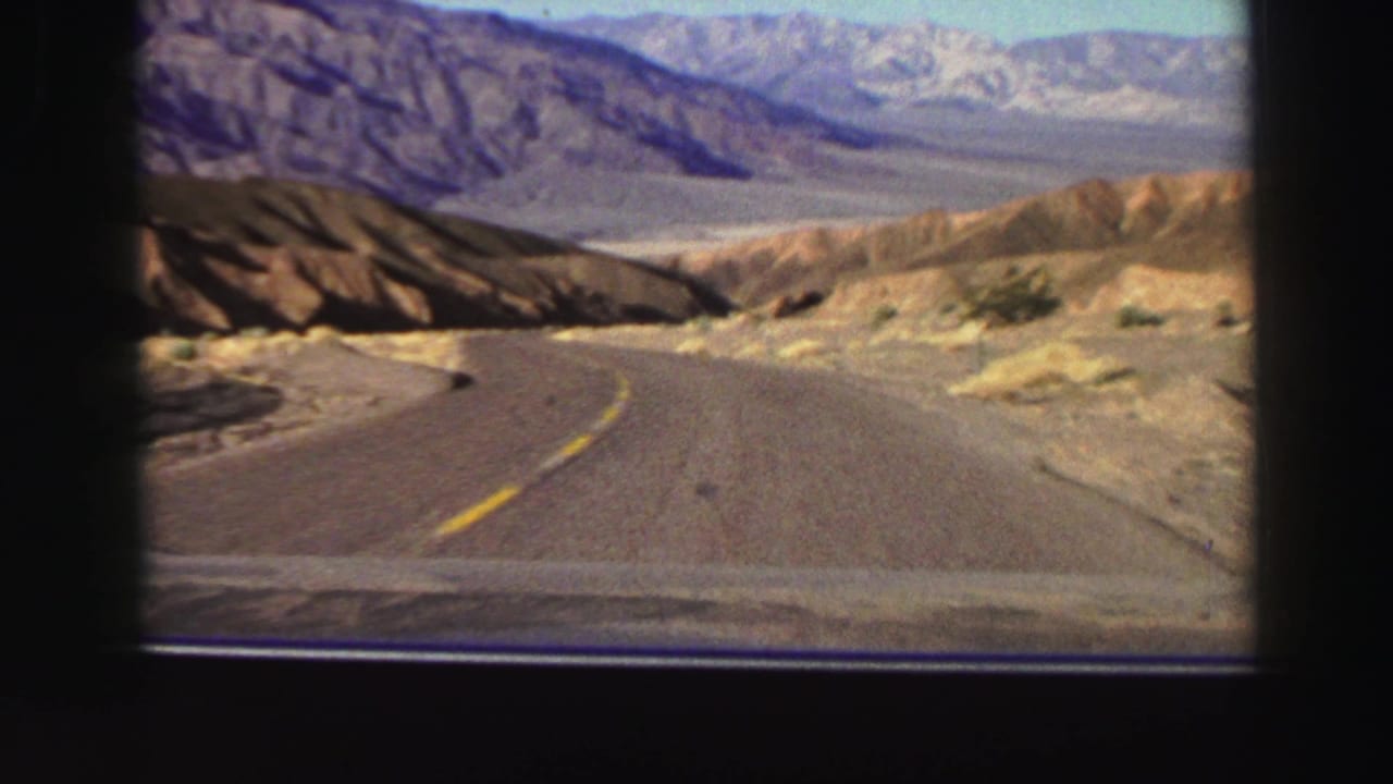 1969 8mm travel view from a car on a curving road through arid mountain country near the Lake Tahoe, California metadata location.