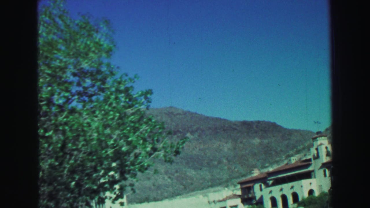 Trees and mountain slopes with part of a church building entering the roadside frame.