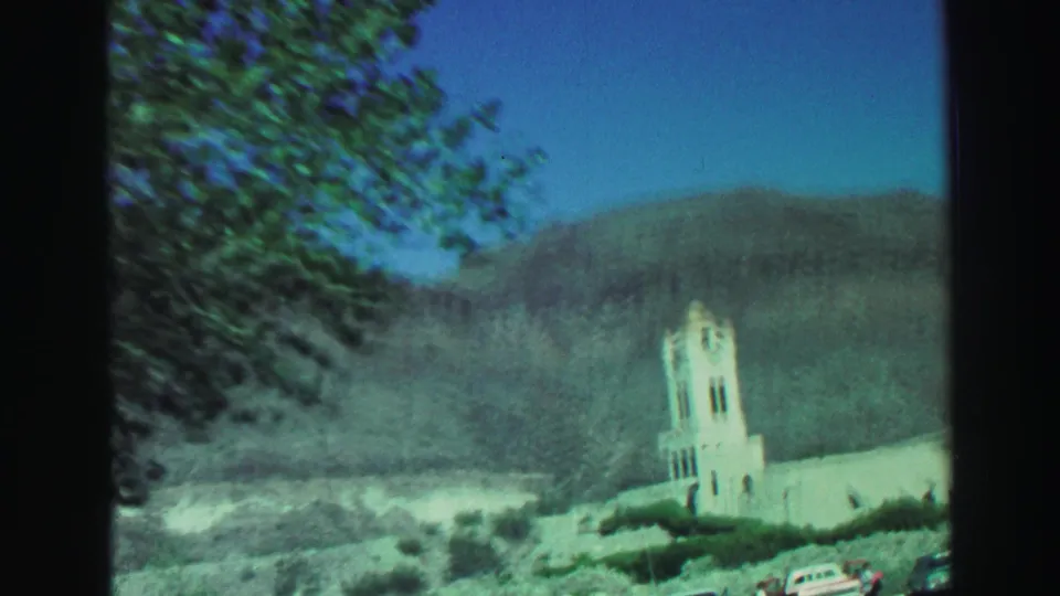 White church bell tower in Lake Tahoe, California, seen below dry mountain slopes with trees framing the passing 8mm view.