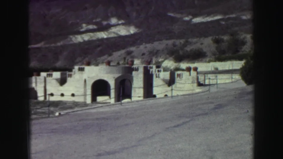 1969 Lake Tahoe exterior showing a Spanish-style stucco building with arched doorways, road foreground, and hillside in back.