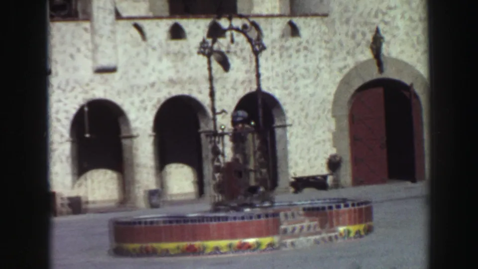 1969 Lake Tahoe courtyard detail showing arched stucco openings, a red door, tiled fountain edge, and bench.