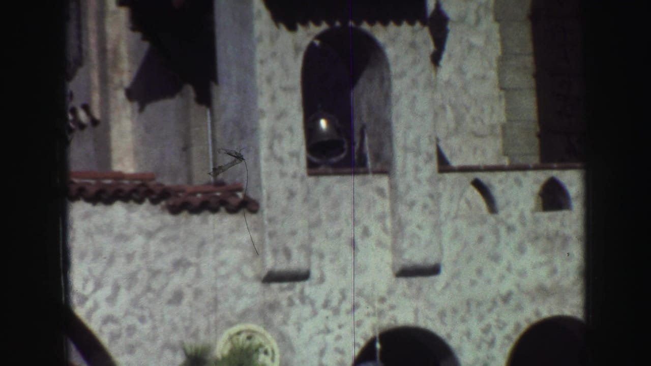 White stucco-like building with arched window openings and a bell near the top.