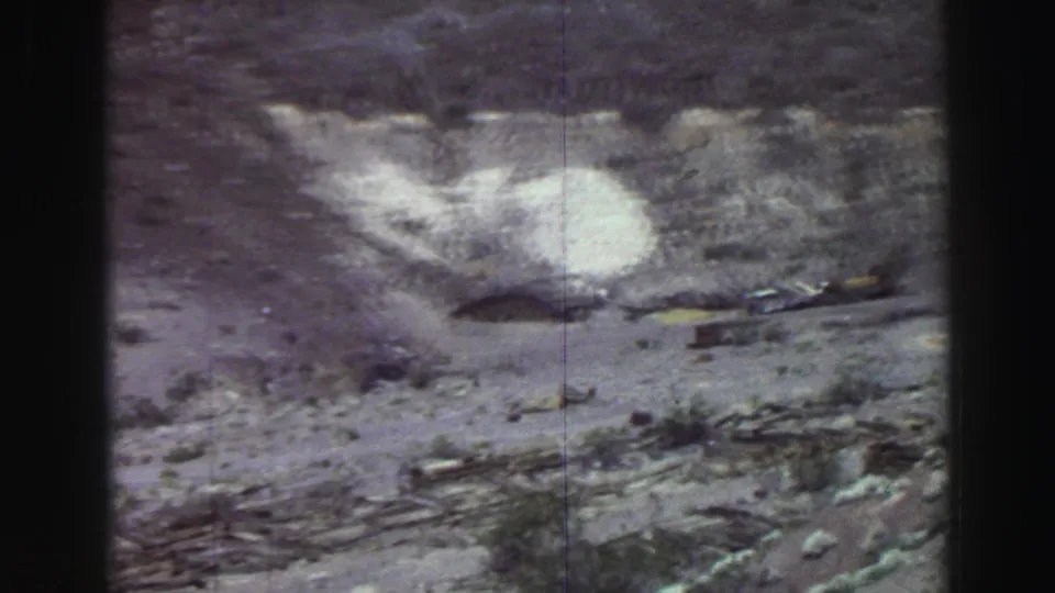 Lake Tahoe 1969 frame with a bright hillside patch, rough rocky ground, sparse brush, and a narrow dirt path.