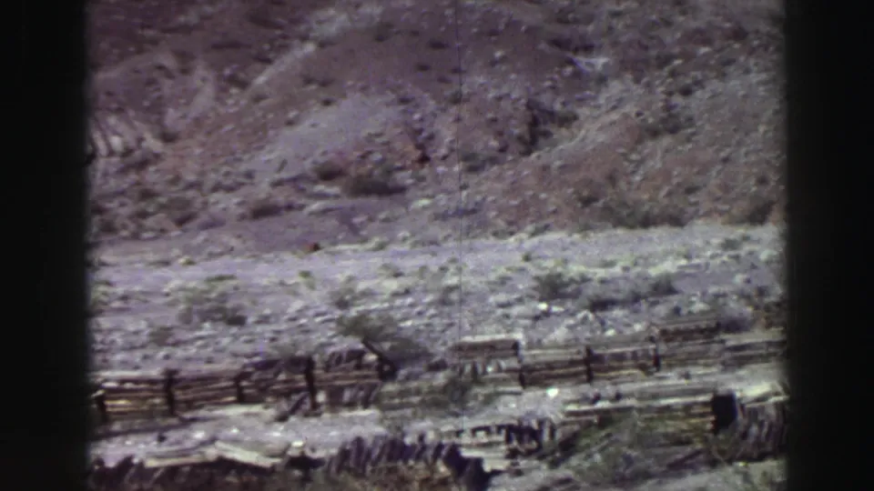 The pan continues across Lake Tahoe terrain with a rough fence, dry stones, and sparse vegetation visible in faded 8mm color.