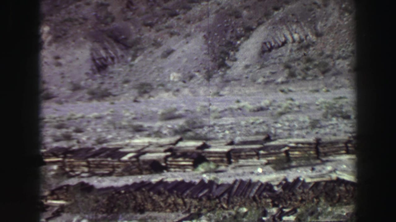 Rocky mountain slope and layered terrain seen through dark 8mm frame edges.