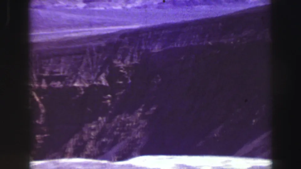Purple-shifted 1969 Lake Tahoe landscape frame with a rugged cliff face and pale foreground strip.