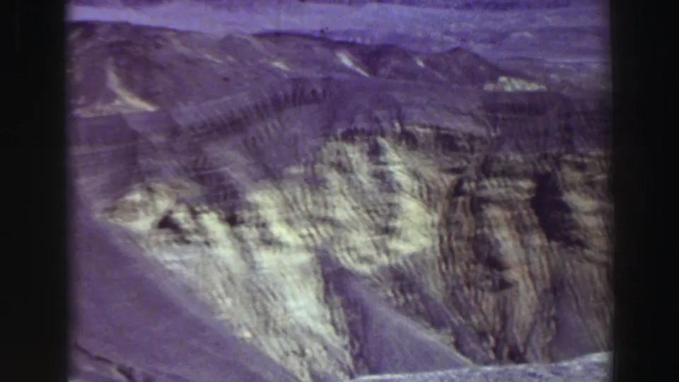 Purple-shifted 8mm frame of eroded canyon terrain and distant hills, described in metadata as Lake Tahoe, California, 1969.