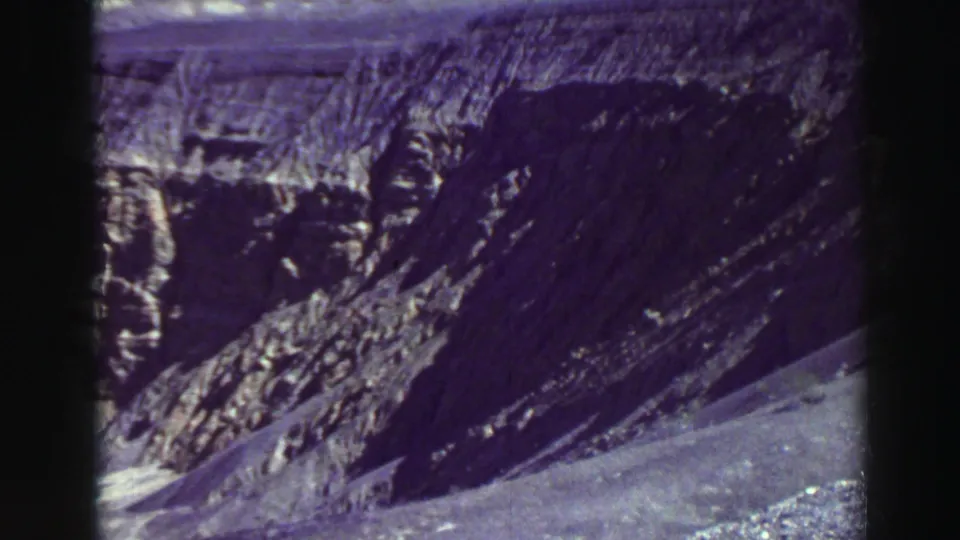 Aged 8mm frame of a steep canyon wall and washed-out dirt slope near Lake Tahoe, with purple color shift and soft focus.