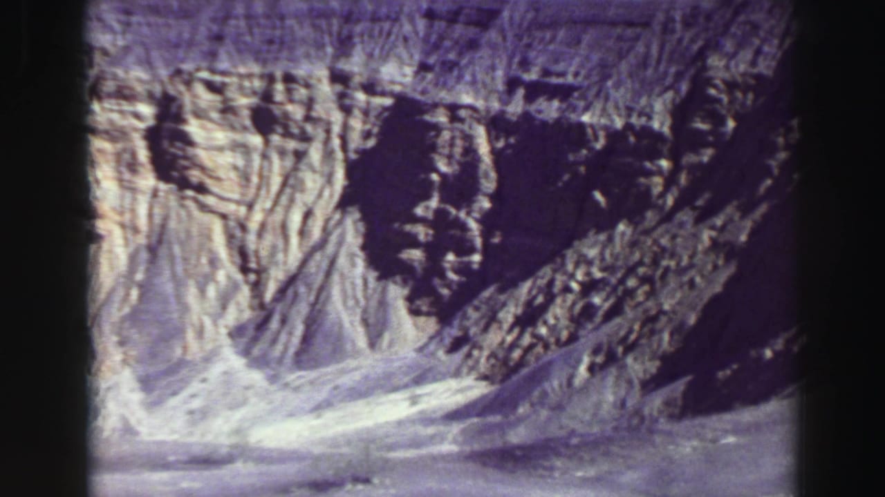 Sunlit rocky canyon wall and pale scree slopes with dark shadowed cliffs.