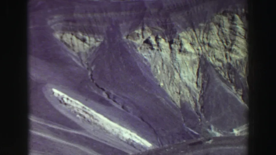 1969 8mm Lake Tahoe-area view of a triangular talus slope, jagged canyon walls, and bright rock surfaces framed by aged film edges.