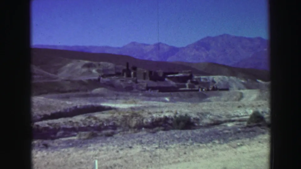 Vintage 8mm frame of ruins in a dry landscape near Lake Tahoe, with blue mountains and open sky in the background.