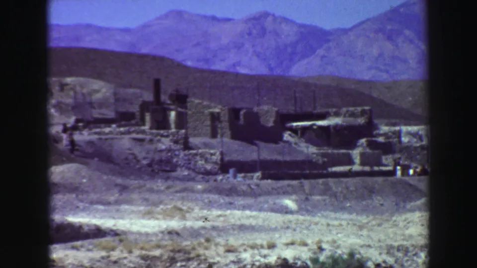 Close 8mm frame near Lake Tahoe showing weathered ruins, low wall lines, dry terrain, and a mountain backdrop.