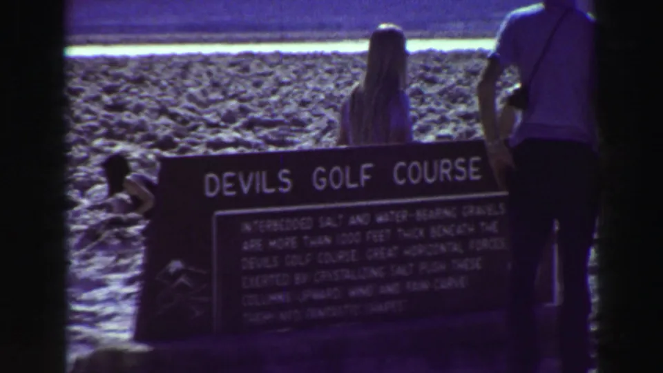 Visitors stand near a Devils Golf Course interpretive sign in vintage 8mm travel footage from the stated 1969 clip.
