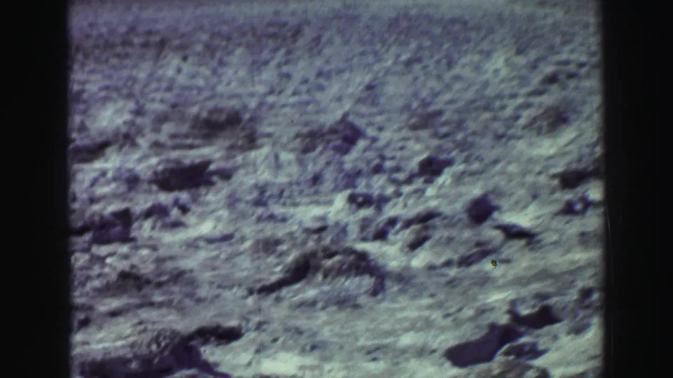 1969 Lake Tahoe-area 8mm frame showing rough rocky ground, shallow hollows, and sparse vegetation.