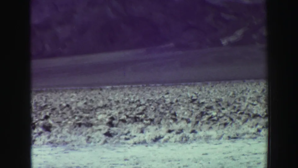 1969 8mm home-movie frame of distant rugged mountains and a rocky roadside in the Lake Tahoe, California area.