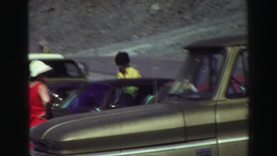 Travelers in casual late-1960s clothing stand near vintage cars at a roadside stop in Lake Tahoe-area home-movie footage.