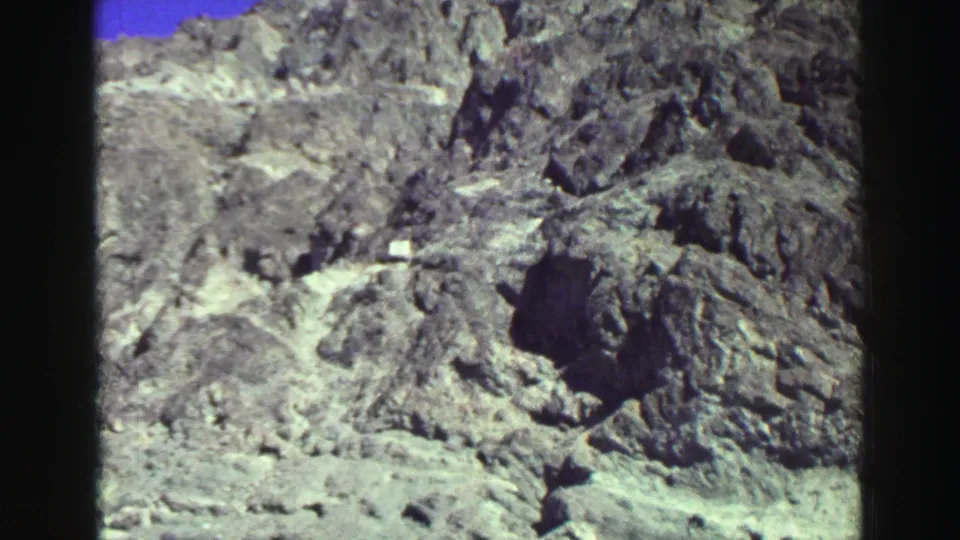 Rocky Lake Tahoe shoreline detail with dark stones, pale gravel, and visible film artifacting from the 8mm scan.