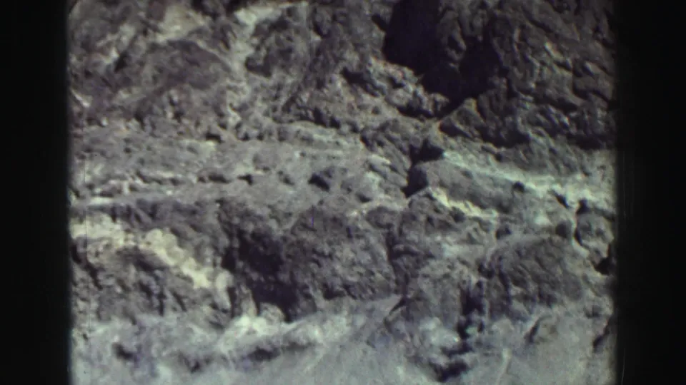 1969 Lake Tahoe frame dominated by a rough gray rocky slope, with the walking figures no longer clearly visible.