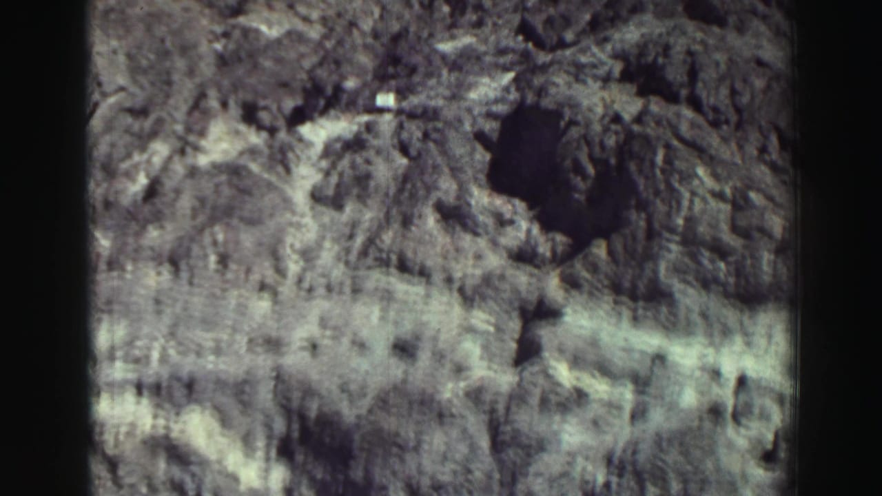 Rocky cliff face under blue sky with dark shadowed openings.