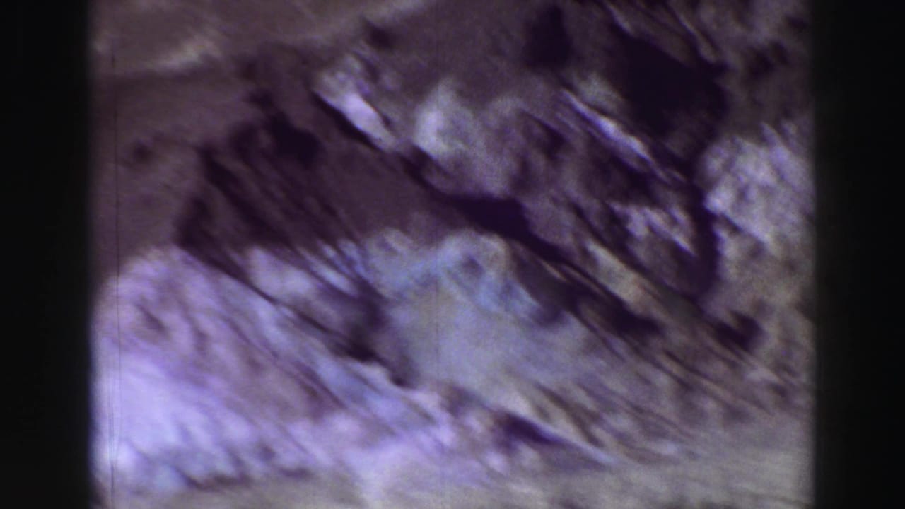 Soft, purple-toned view of rugged rocky mountain slopes with dark film borders.