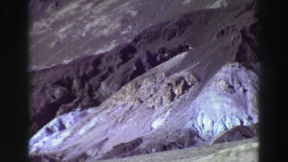 1969 Lake Tahoe mountain view with pale eroded slopes, darker rock bands, and bright sunlit terrain.