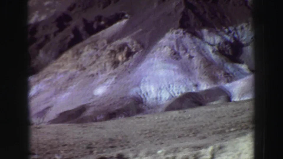 1969 8mm view near Lake Tahoe showing a barren foreground and layered eroded mountain slopes.